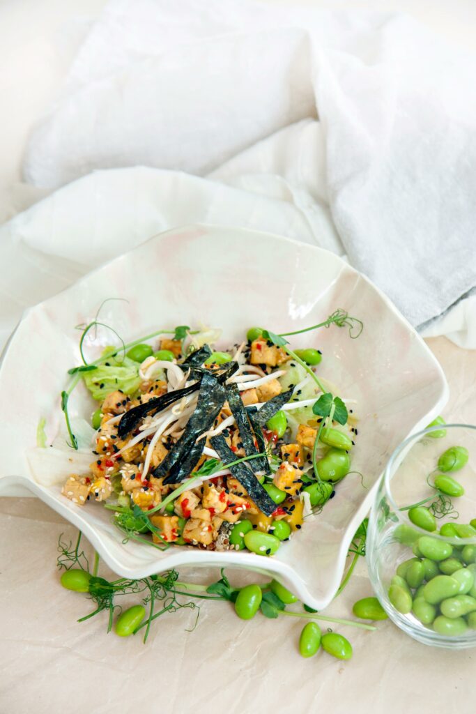 A vibrant vegetarian salad featuring edamame, quinoa, and fresh vegetables, artfully presented.