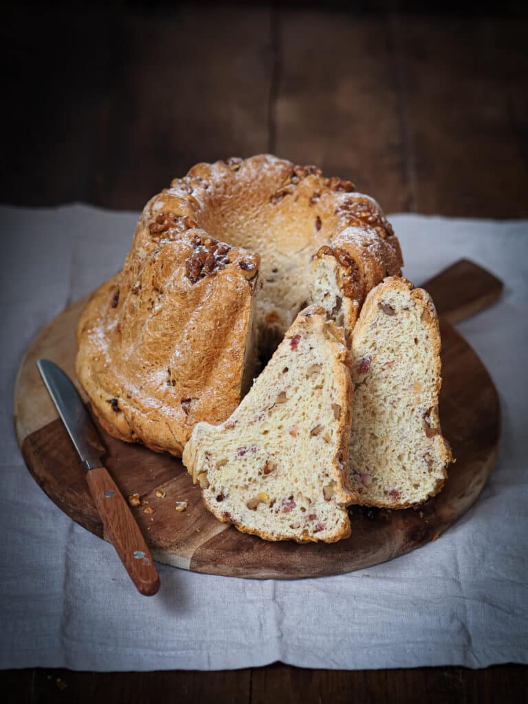 Kougelhopf salés découpé en tranches sur un plateau en bois posé sur un tissu en lin