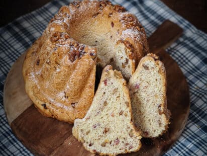 Kougelhopf salé aux lardons et aux noix et tranches découpées et présentées sur une planche en bois posée sur un tissu en kelsch alsacien