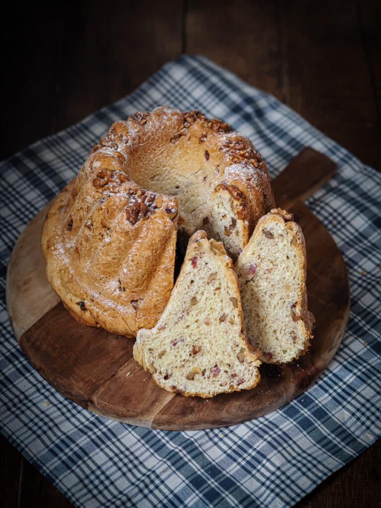 Kougelhopf salé aux lardons et aux noix et tranches découpées et présentées sur une planche en bois posée sur un tissu en kelsch alsacien