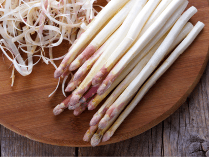 Asperges blanches fraîches sur planche en bois