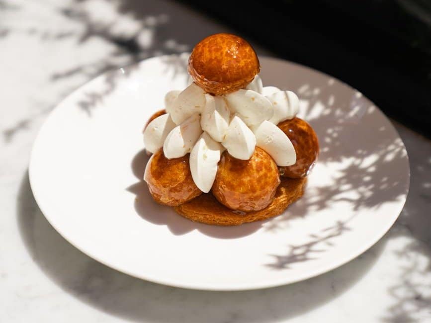 Saint-Honoré individuel : choux caramélisés et crème chantilly sur une assiette blanche